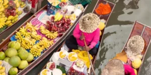 Mercato galleggiante tailandese con venditori su barche piene di frutta esotica