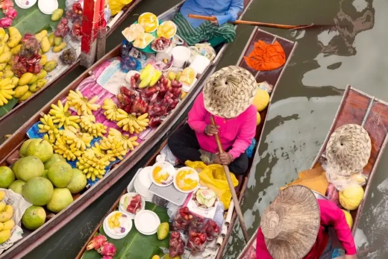 Mercato galleggiante tailandese con venditori su barche piene di frutta esotica