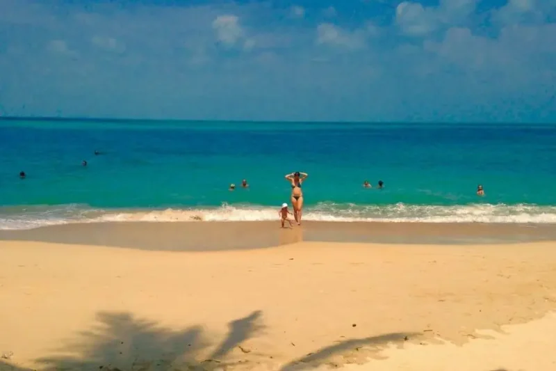 Spiaggia tropicale con mare azzurro e bagnanti sotto il sole