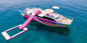 Catamarano con scivolo rosa e piattaforma galleggiante nel mare blu