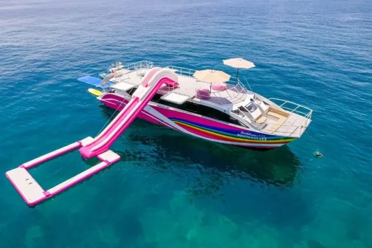 Catamarano con scivolo rosa e piattaforma galleggiante nel mare blu