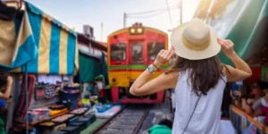 Mercato thailandese con treno in arrivo tra le bancarelle affollate