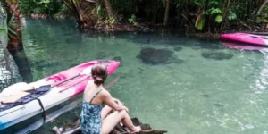 Donna in costume da bagno osserva kayak sulla laguna Bor Thor nella foresta pluviale