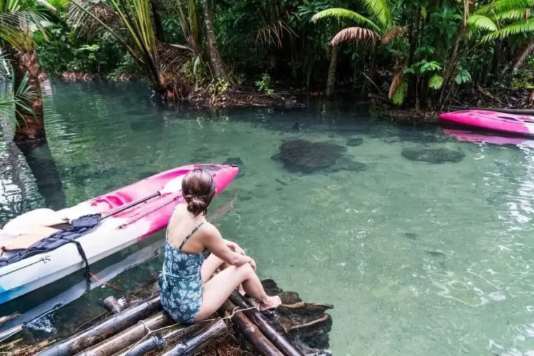 Donna in costume da bagno osserva kayak sulla laguna Bor Thor nella foresta pluviale