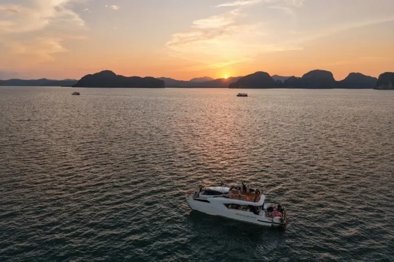 Tramonto su baia con barche e orizzonte montuoso Serenity Cruise Phang Nga Bay
