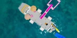 Piattaforma galleggiante con scivolo rosa su mare cristallino