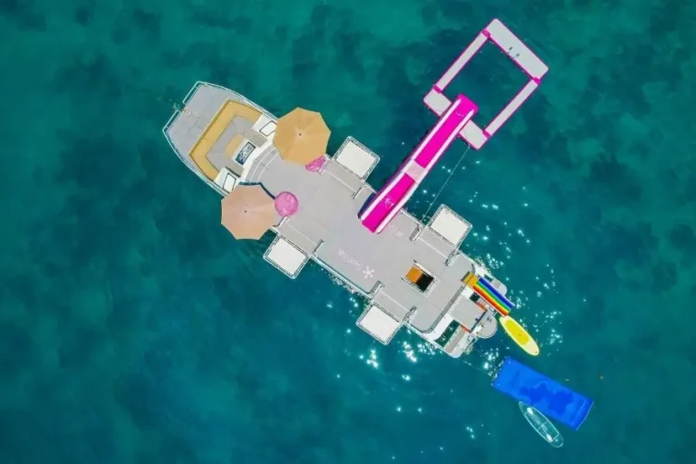 Piattaforma galleggiante con scivolo rosa su mare cristallino