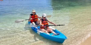 Due persone navigano su un kayak blu in una spiaggia tropicale a Koh Hong