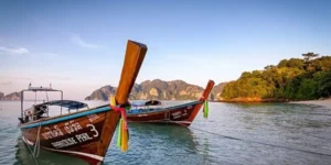 Barche tradizionali tailandesi ancorate vicino a una spiaggia tropicale