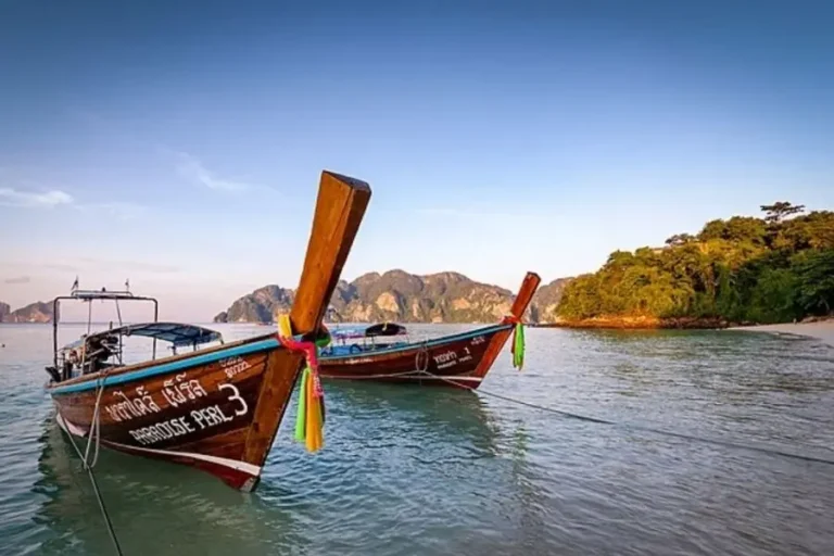 Barche tradizionali tailandesi ancorate vicino a una spiaggia tropicale