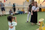 Una bambina thailandese scatta una foto ricordo a due turisti sulla terrazza panoramica del Wat Saket a Bangkok durante il tramonto.