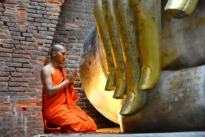 Monaco Buddhista prega a Sukhothai 8 Guida Bangkok 2026: Info e Consigli Utili per organizzare Tour ed Escursioni in Thailandia Monaco buddista in preghiera davanti a statua dorata in un tempio antico