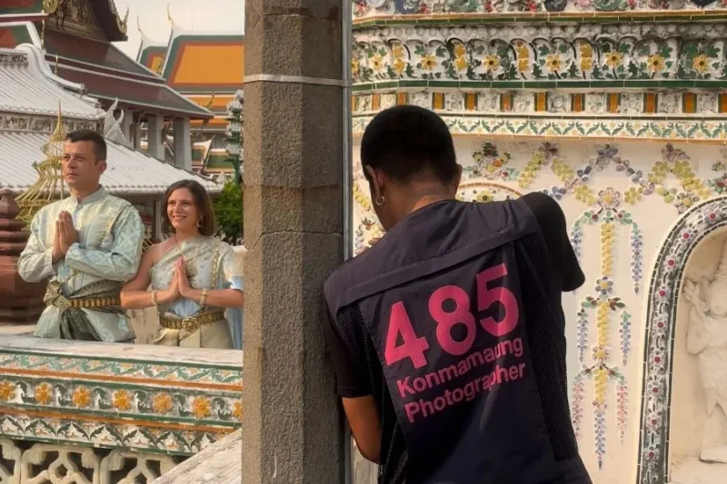 Turisti posano in abiti tradizionali tailandesi per una foto a un tempio