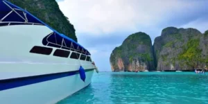 Barca a motore nelle acque cristalline di Maya Bay, Thailandia, con scogliere lussureggianti sullo sfondo