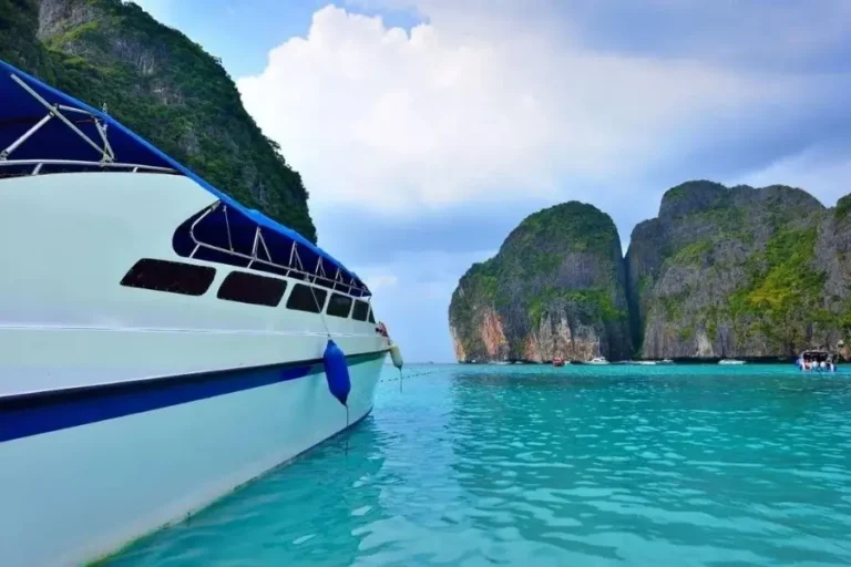 Barca a motore nelle acque cristalline di Maya Bay, Thailandia, con scogliere lussureggianti sullo sfondo