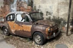 Auto d'epoca arrugginita parcheggiata vicino a un muro di mattoni - Talat Noi