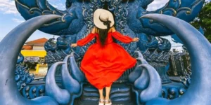 Donna in abito rosso su struttura blu del Tempio Blu in Thailandia