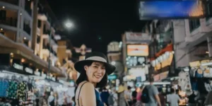 Donna sorridente con cappello in un mercato notturno affollato