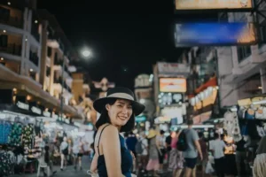 Donna sorridente con cappello in un mercato notturno affollato