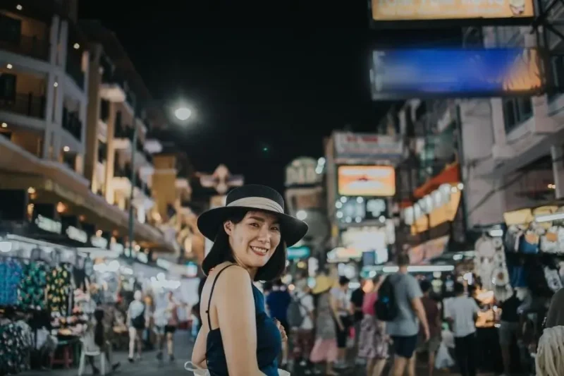 Donna sorridente con cappello in un mercato notturno affollato