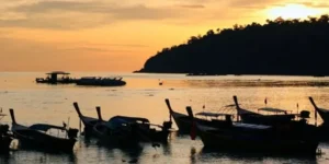 Barche tradizionali in mare al tramonto su spiaggia thailandese