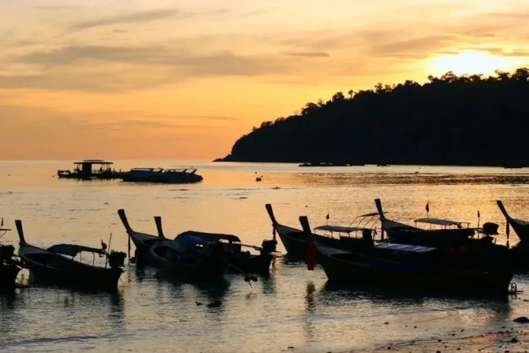 Barche tradizionali in mare al tramonto su spiaggia thailandese