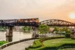 Treno su ponte storico sul fiume Kwai al tramonto