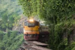 Locomotiva gialla attraversa un ponte ferroviario in una foresta lussureggiante
