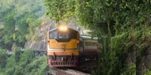 Locomotiva gialla attraversa un ponte ferroviario in una foresta lussureggiante