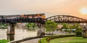 Treno su ponte storico sul fiume Kwai al tramonto