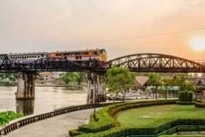 Treno su ponte storico sul fiume Kwai al tramonto