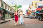 Due donne passeggiano in una vivace strada asiatica con tuk-tuk