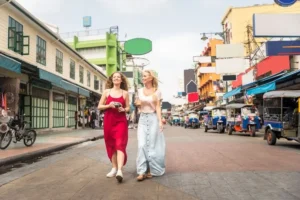 Due donne passeggiano in una vivace strada asiatica con tuk-tuk