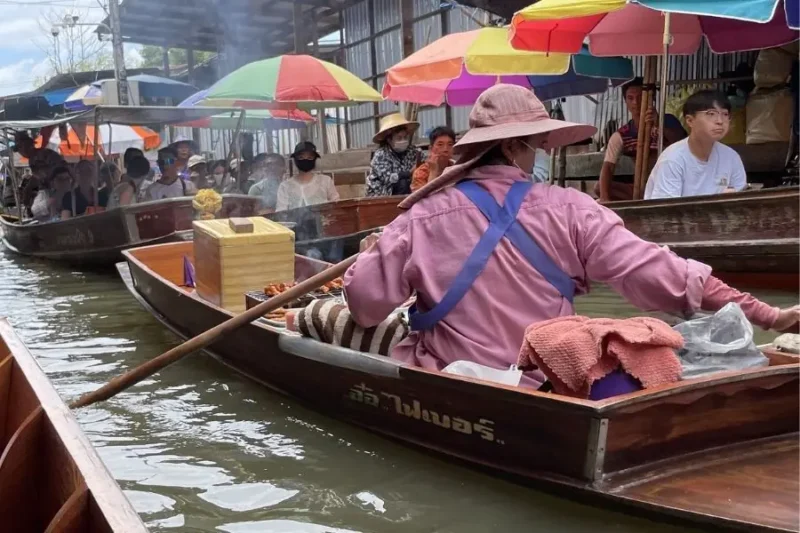 Mercato galleggiante con barche e venditori lungo un canale affollato