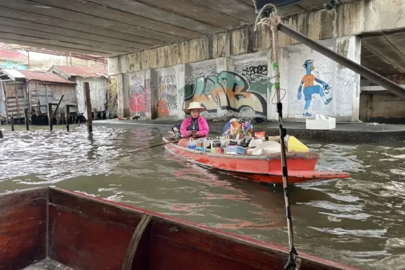 Venditrice su barca nel mercato galleggiante sotto il ponte