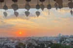 Tramonto panoramico su Bangkok visto dal tempio Wat Saket (Monte d'Oro), con campanelle buddhiste tipiche in primo piano.