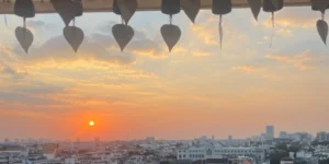 Tramonto panoramico su Bangkok visto dal tempio Wat Saket (Monte d'Oro), con campanelle buddhiste tipiche in primo piano.